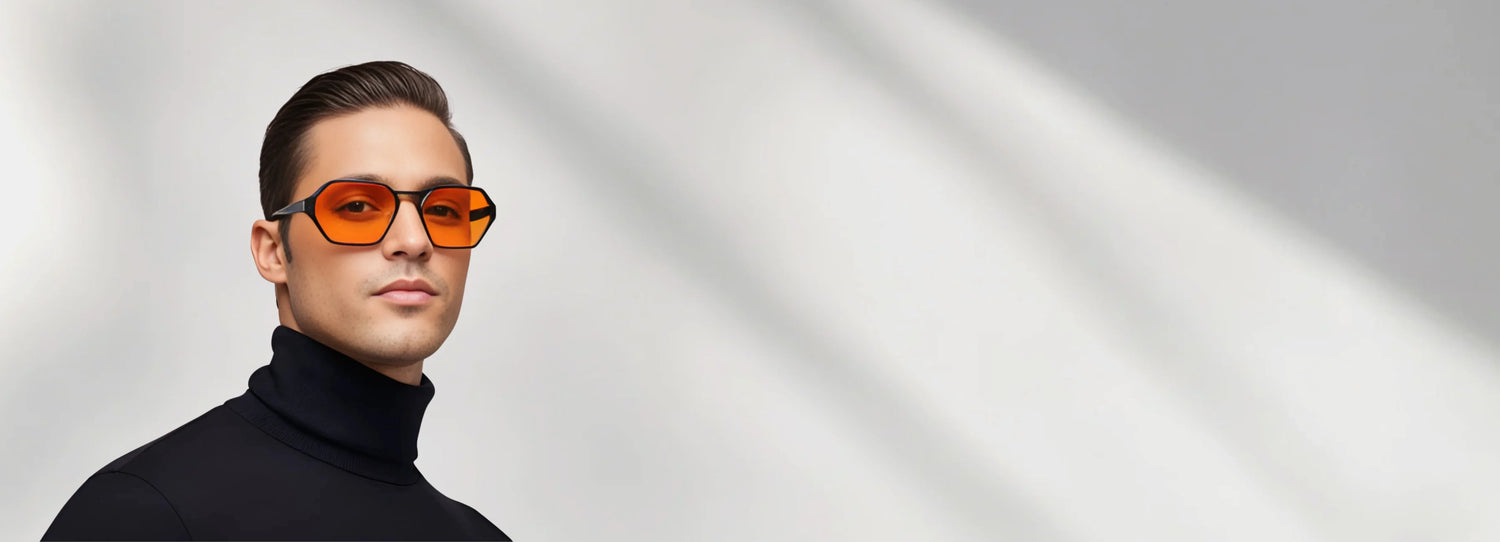 Man wearing orange-tinted sunglasses against a gray background